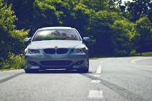 Серебристый BMW 5 series перед поворотом в лес